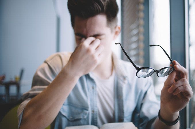 Man, experiencing eye fatigue, wipes his eyes.