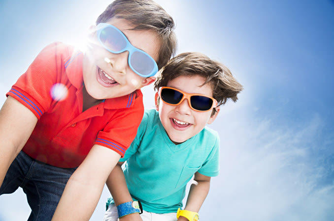 Small children wearing sunglasses outside.