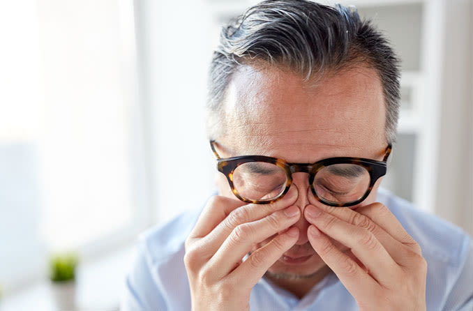 man rubbing eyes from eye pain