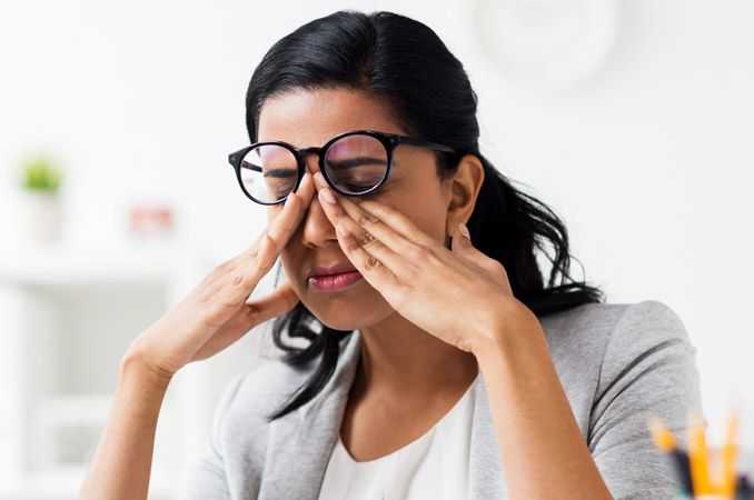 Woman rubbing her eyes to deal with eyelid twitching.