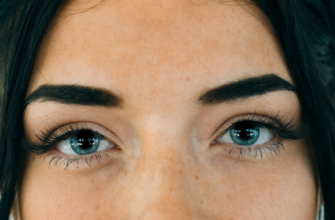 Woman with black hair and blue eyes with dilated pupils.