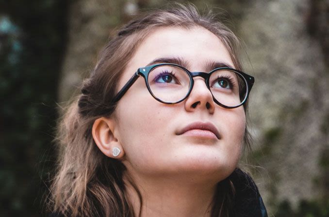 Woman wearing glasses, looking up.