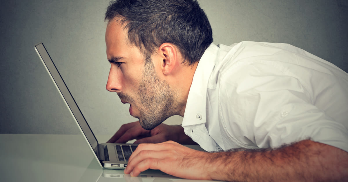 man squints at laptop screen without reading spectacles