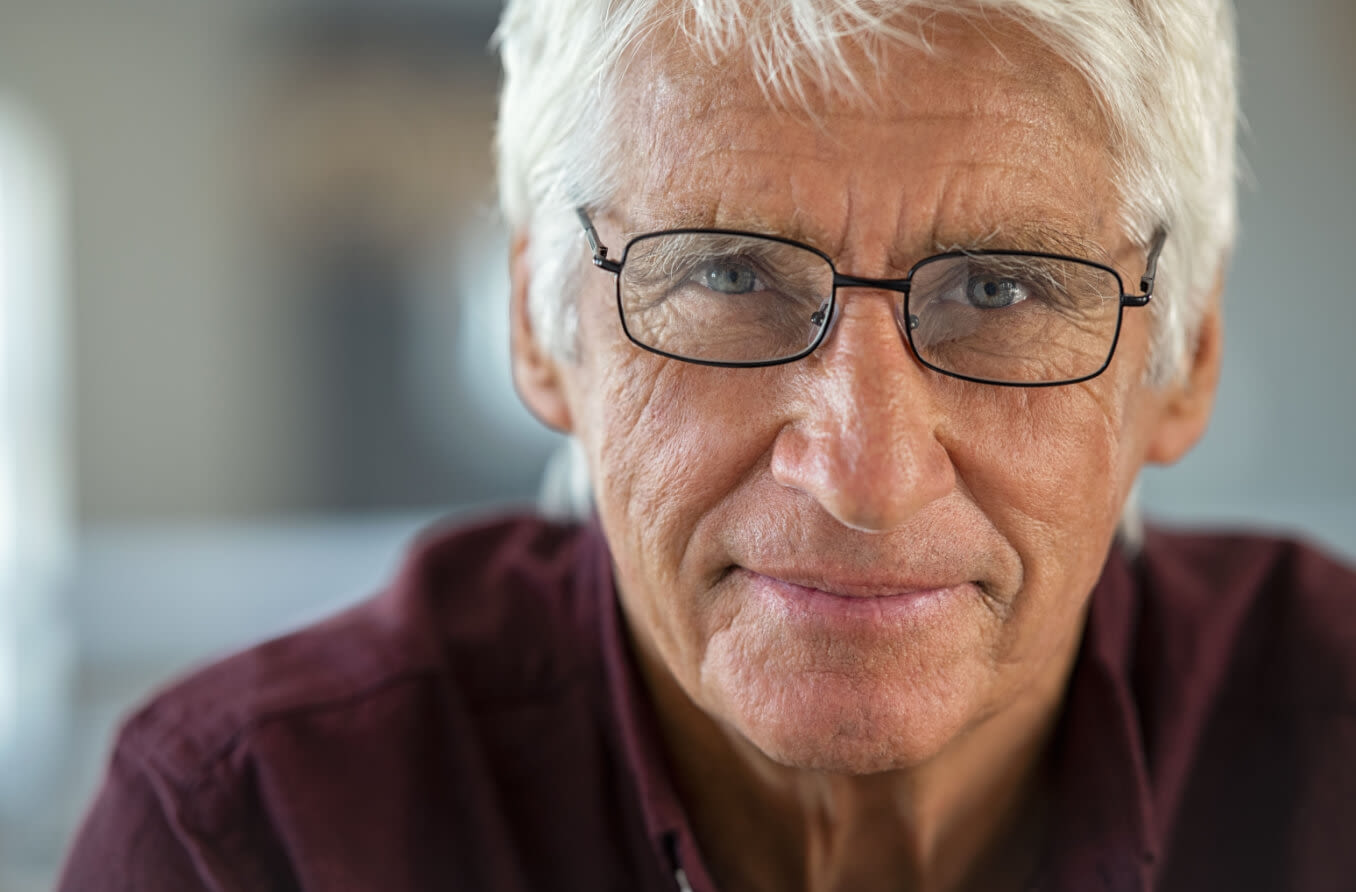 senior woman wearing glasses reading the newspaper