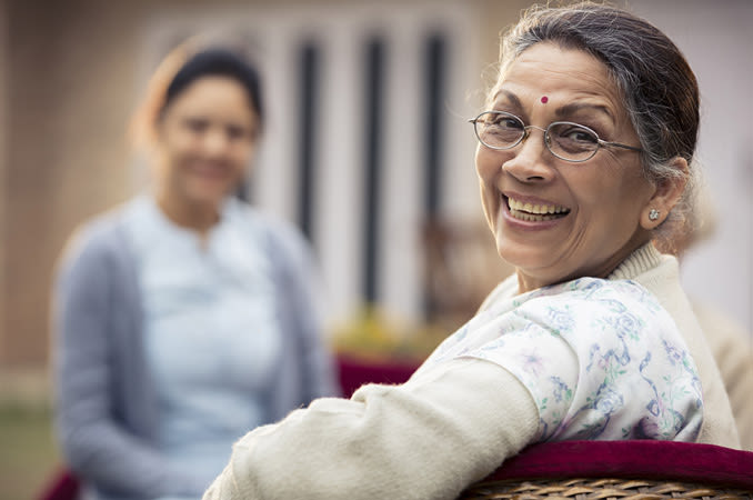 A happy older Indian woman wearing glasses smiling.