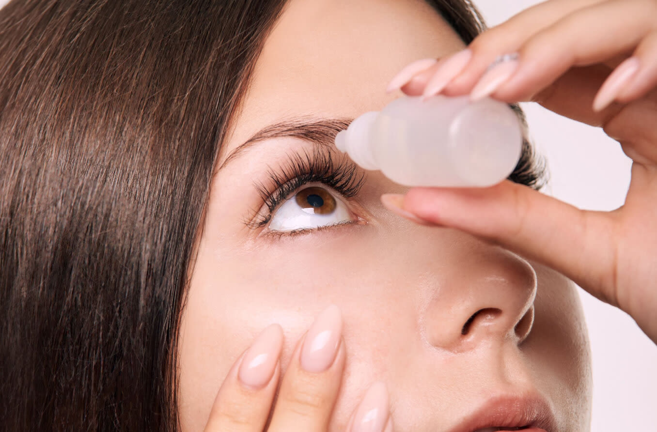 Woman putting eyedrops into eye